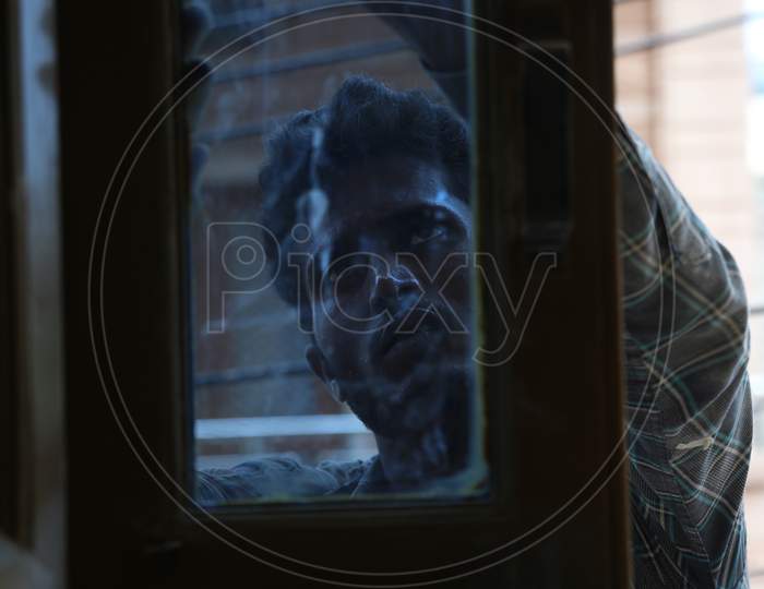 Jodhpur, Rajasthan, India, 20Th September 2020: Indian Young Male Labour Worker Repairing Dark Tinted Window Frames For Home Furnishing, Through Glass Window View.