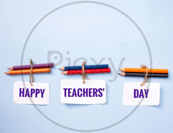Happy Teacher's Day Wish Written On Paper Note With Color Pencils On Pink Background