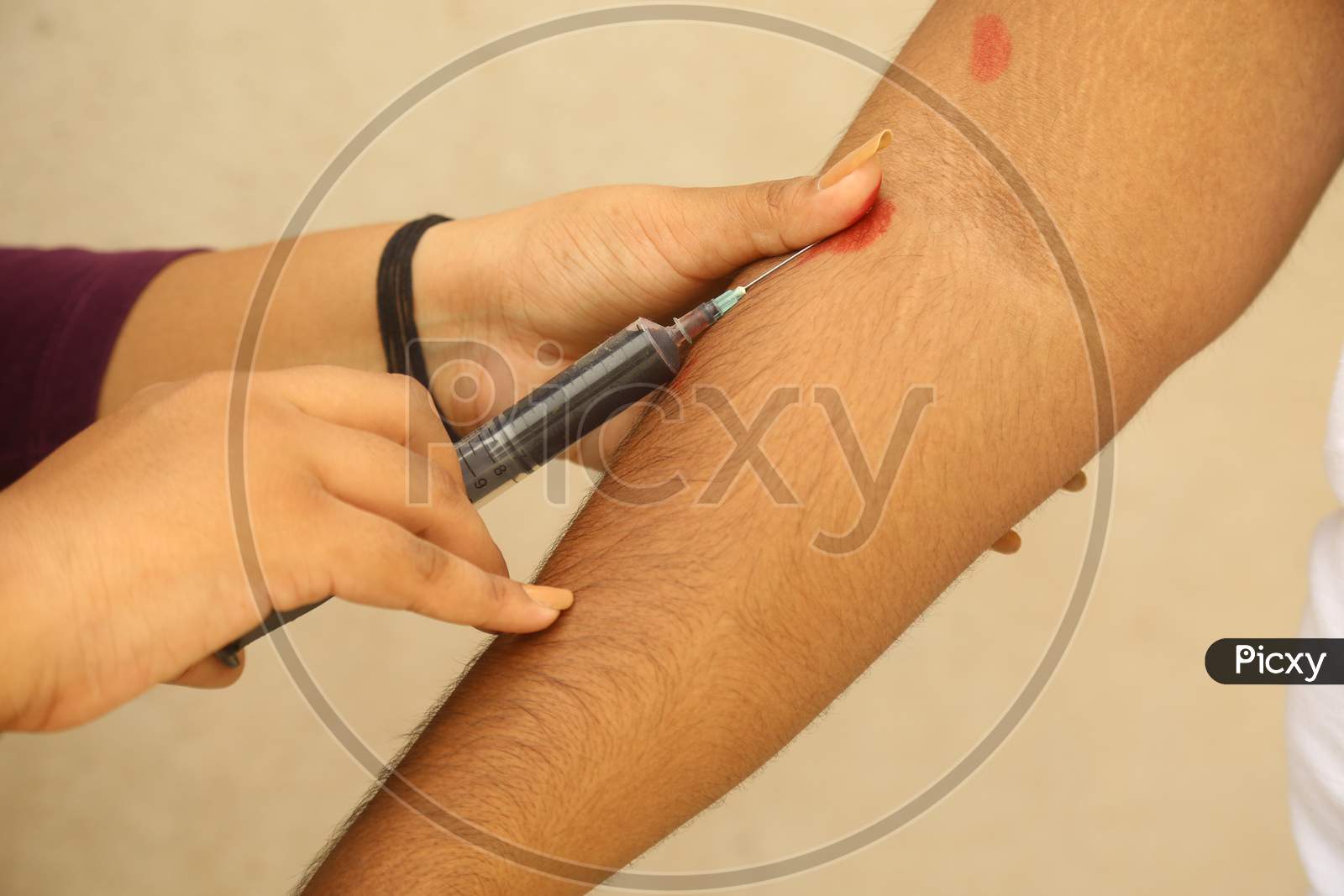 Young Indian Girl Taking Vein Blood Sample Of A Man Through A Syringe For A Rapid Test Of Coronavirus In India, Against Wall Background, Covis 19, Antibody Test