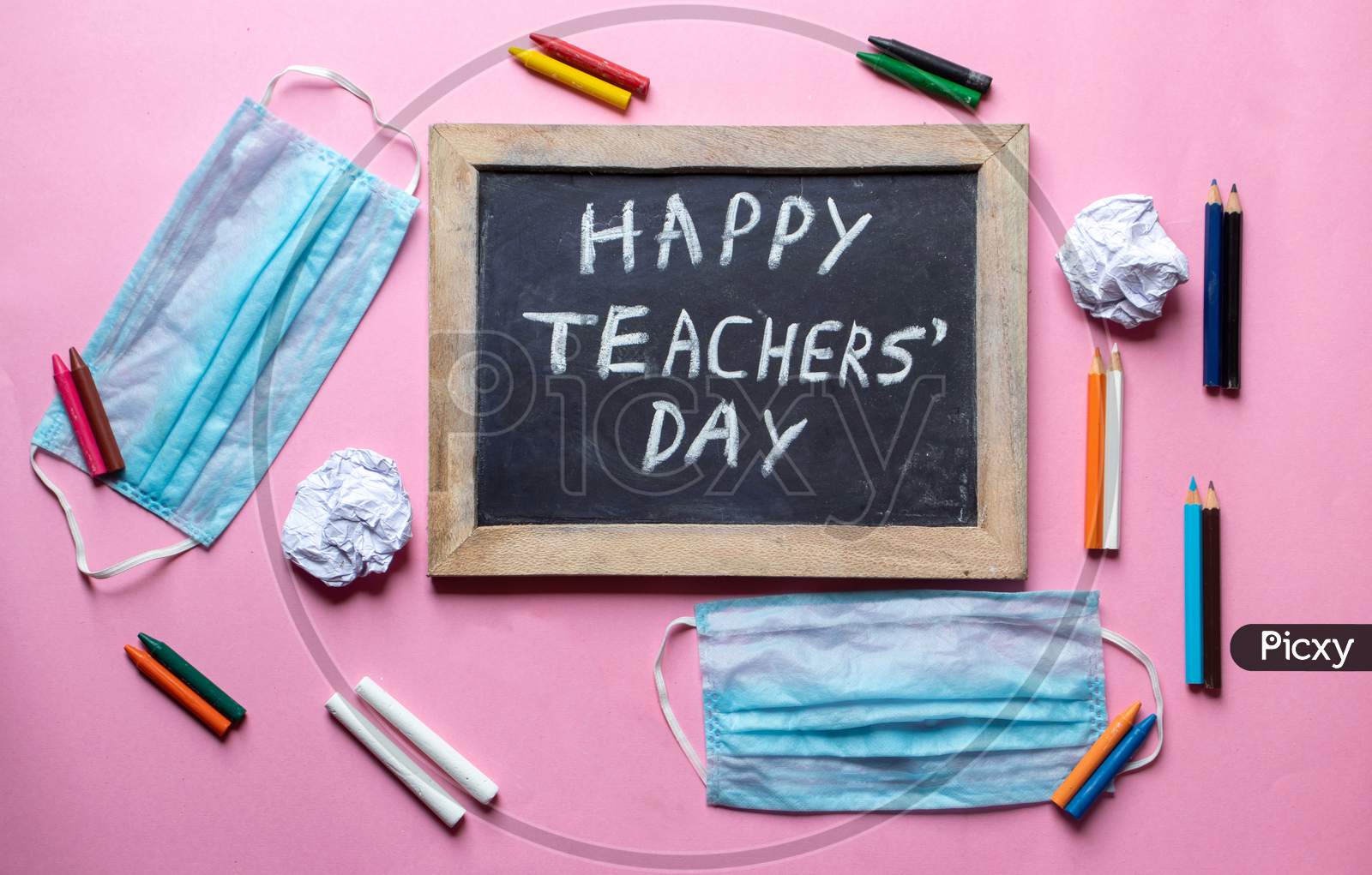 Happy Teacher's Day Creative Photo With Medical Face Mask, Chalkboard And Pencils Isolated On Pink Background, Perfect For Wallpaper
