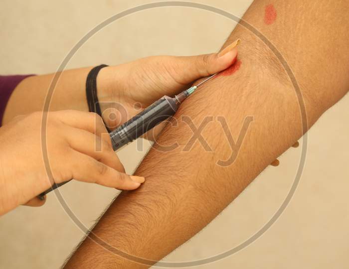 Young Indian Girl Taking Vein Blood Sample Of A Man Through A Syringe For A Rapid Test Of Coronavirus In India, Against Wall Background, Covis 19, Antibody Test