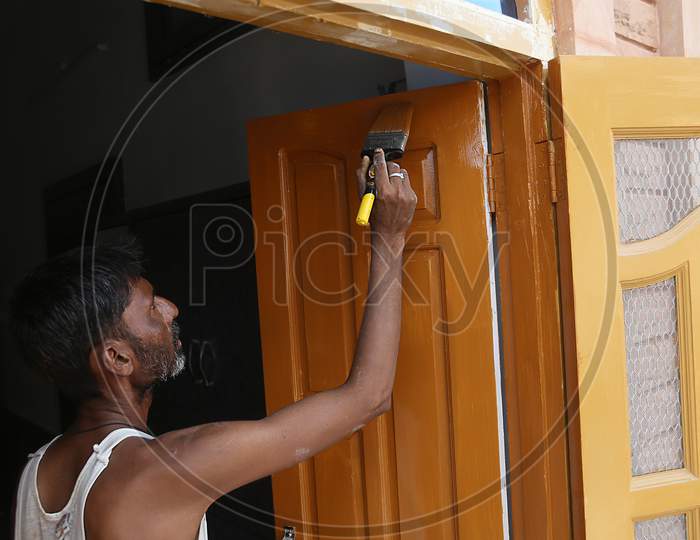 Jodhpur, Rajasthan, India, 20Th September 2020: Indian Male Worker Laboour Painting Brown Wooden Door With Paint Brush In Hand, Home Furnishing Concept, Back To Work After Lockdown Ends In India.