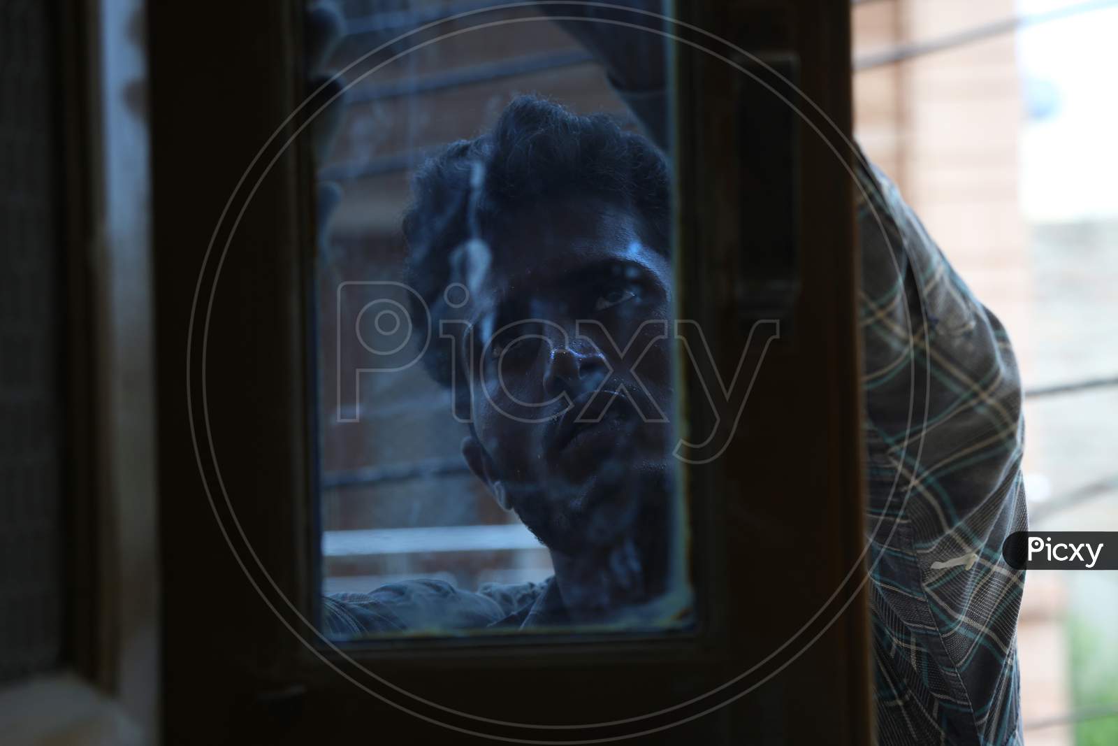 Jodhpur, Rajasthan, India, 20Th September 2020: Indian Young Male Labour Worker Repairing Dark Tinted Window Frames For Home Furnishing, Through Glass Window View.