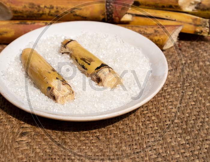 Sugarcane Pieces With Sugar In A Plate On Burlap Fabric With Selective Focus