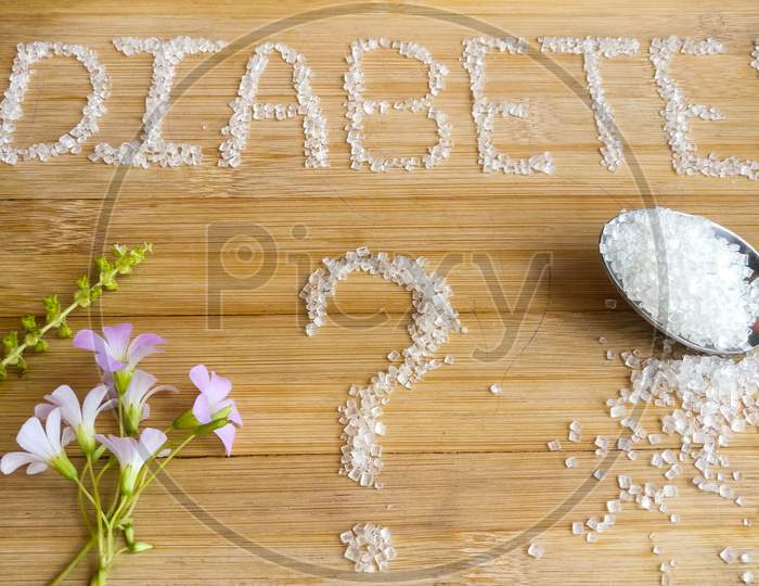 Diabetes written on the wooden table giving massage stay healthy.used Basil, spoon of sugar, flowers, wooden table