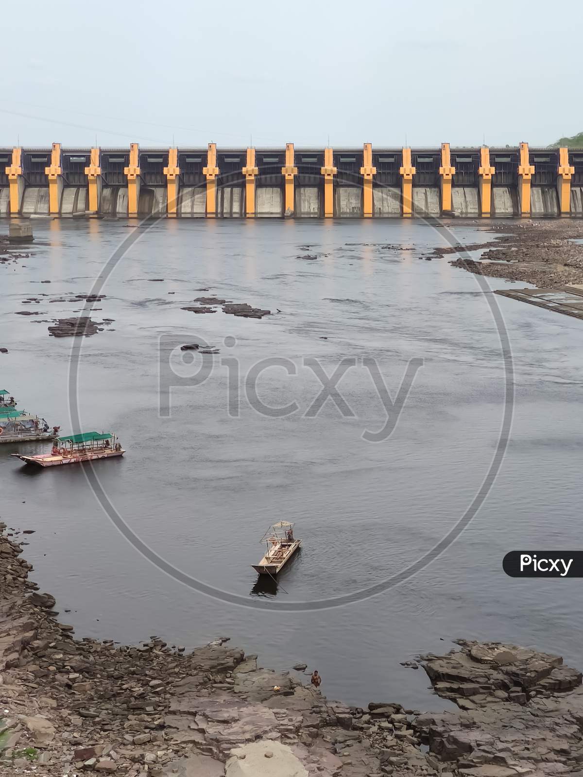 River Narmada with boats standing on the shore and dam in the background