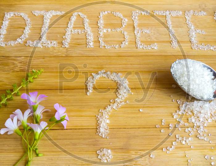 Diabetes written on wooden board with sugar. Tablets, flowers, Basil, spoon of sugar used.top angle shoot