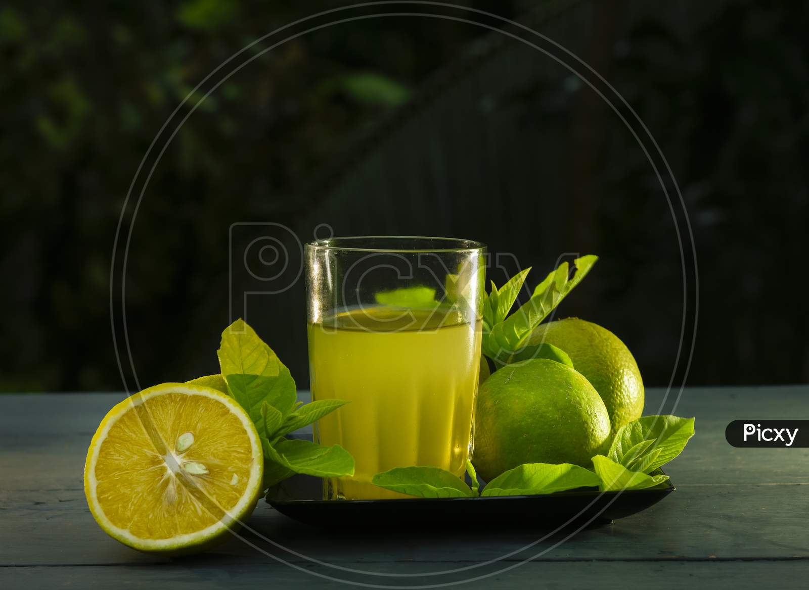 Glass of orange juice and oranges on wooden background