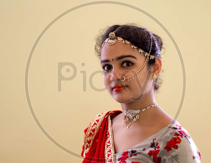 A Beautiful Young Hindu Woman Wore Gold Ornaments And A Colorful Floral Design Choli And Red Odani