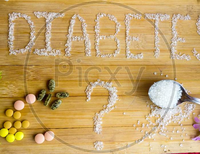 Diabetes written on the wooden table giving massage stay healthy.used Basil, spoon of sugar, flowers, wooden table, tablets