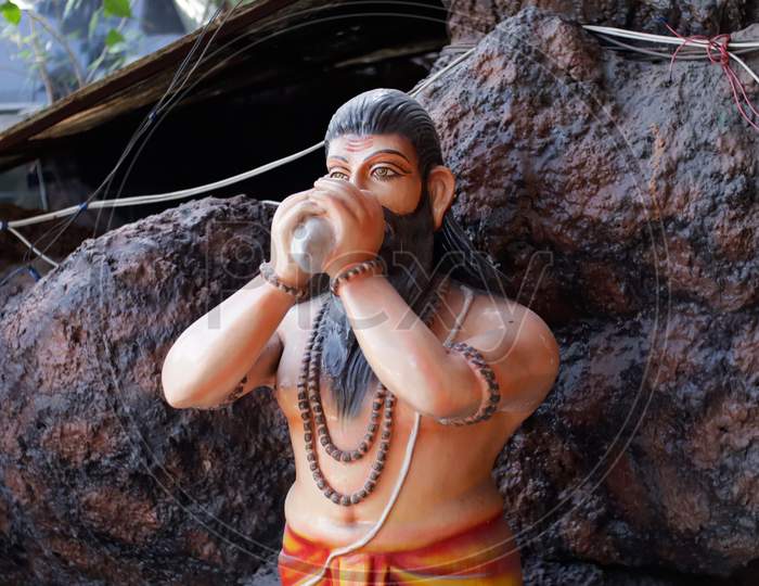 Statue of a HIndu hermit blowing conch placed at temple gate.