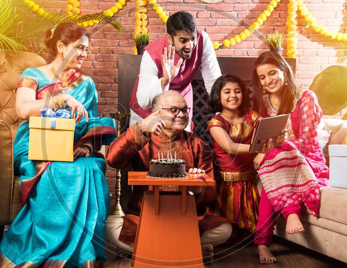 Senior Indian Asian Man Celebrating Birthday With Wife, Son, Daughter In Law And Grand Daughter