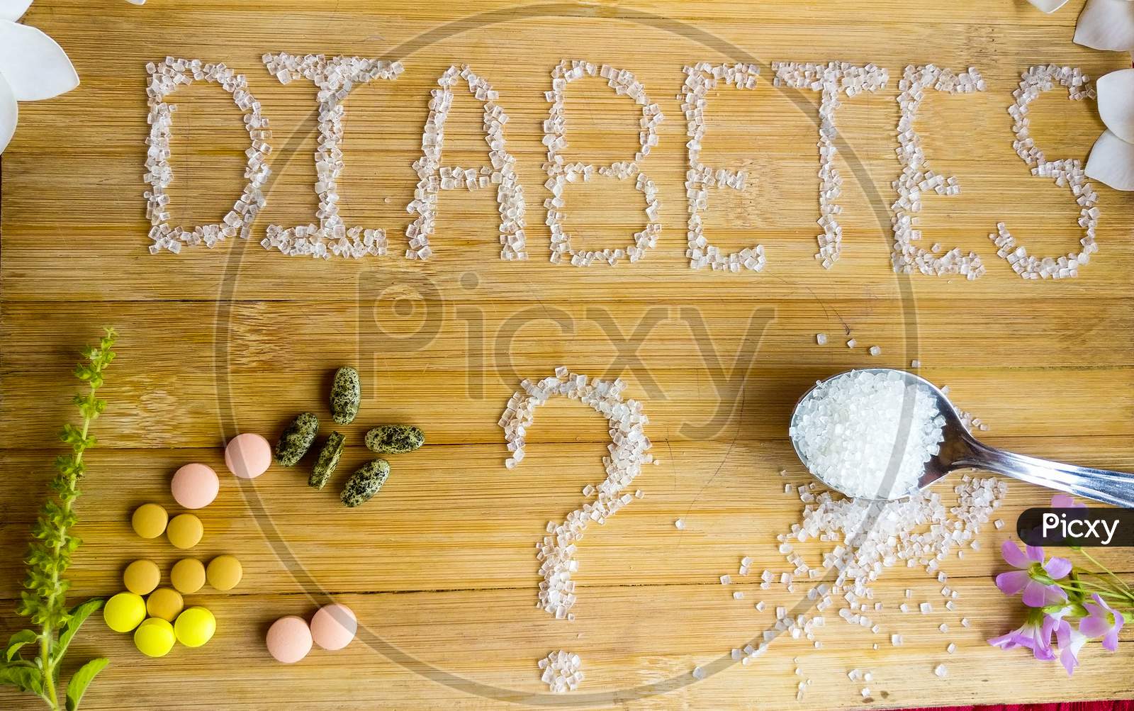 Diabetes written on the wooden table giving massage stay healthy.used Basil, spoon of sugar, flowers, wooden table, tablets