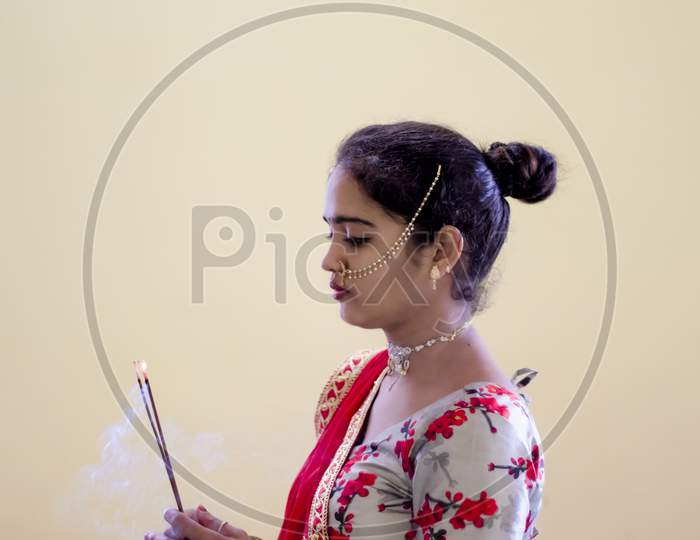 A Beautiful Young Hindu Girl With Incense Sticks Burning With Smoke And Gold Ornaments According To Her Traditions And Customs