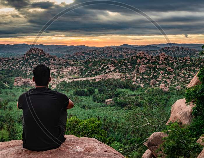 Man Sitting At Mountain Top Watching Sunrise With Dramatic Sky At Morning Flat Angle Shot