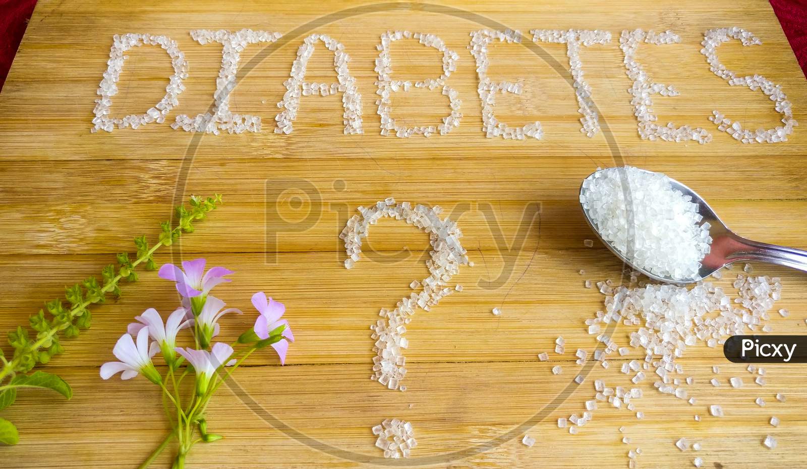 Diabetes written on wooden board with sugar. Tablets, flowers, Basil, spoon of sugar used.top angle shoot