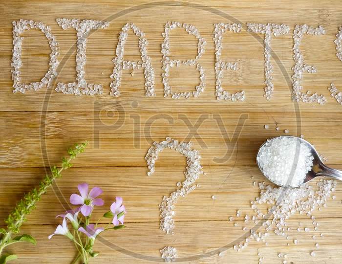 Diabetes written on the wooden table giving massage stay healthy.used Basil, spoon of sugar, flowers, wooden table,
