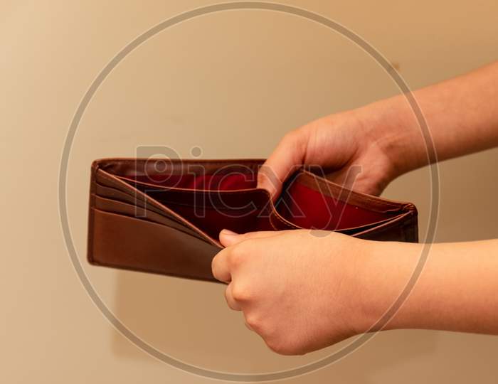 Crop view of Young man hands checking empty brown wallet