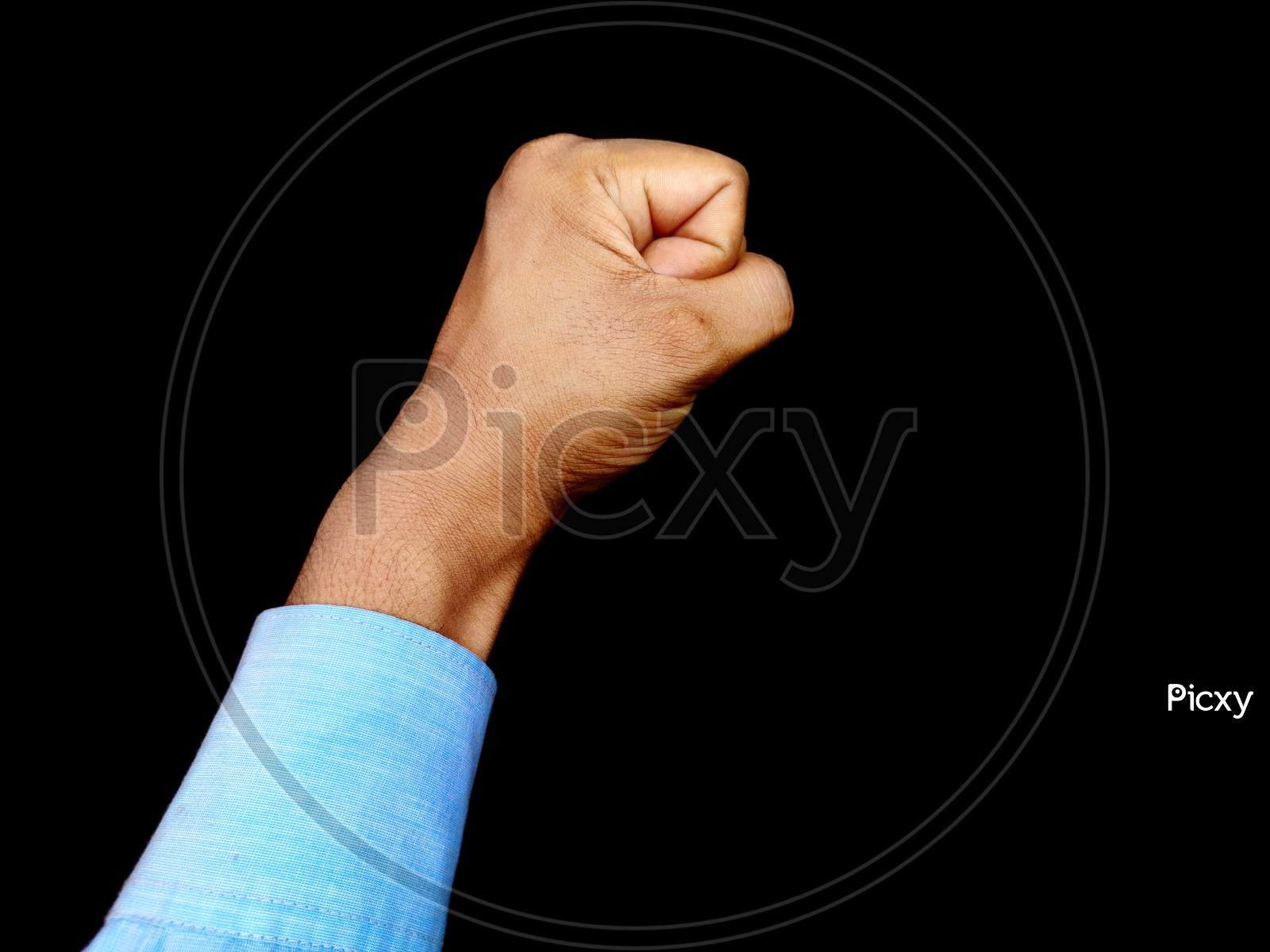 Hand fist of man with blue shirt up in air on black background. Revolution, brave , masculine Concept.