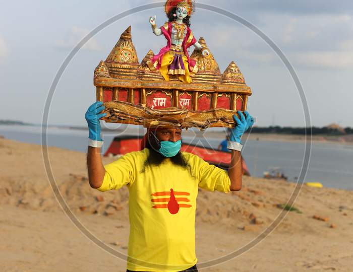 A man holds sculpture of Ram Temple on his head, ahead of the foundation ceremony of Ram temple in Ayodhya, on the banks of River Ganga at Sangam, in Prayagraj, August 4, 2020.