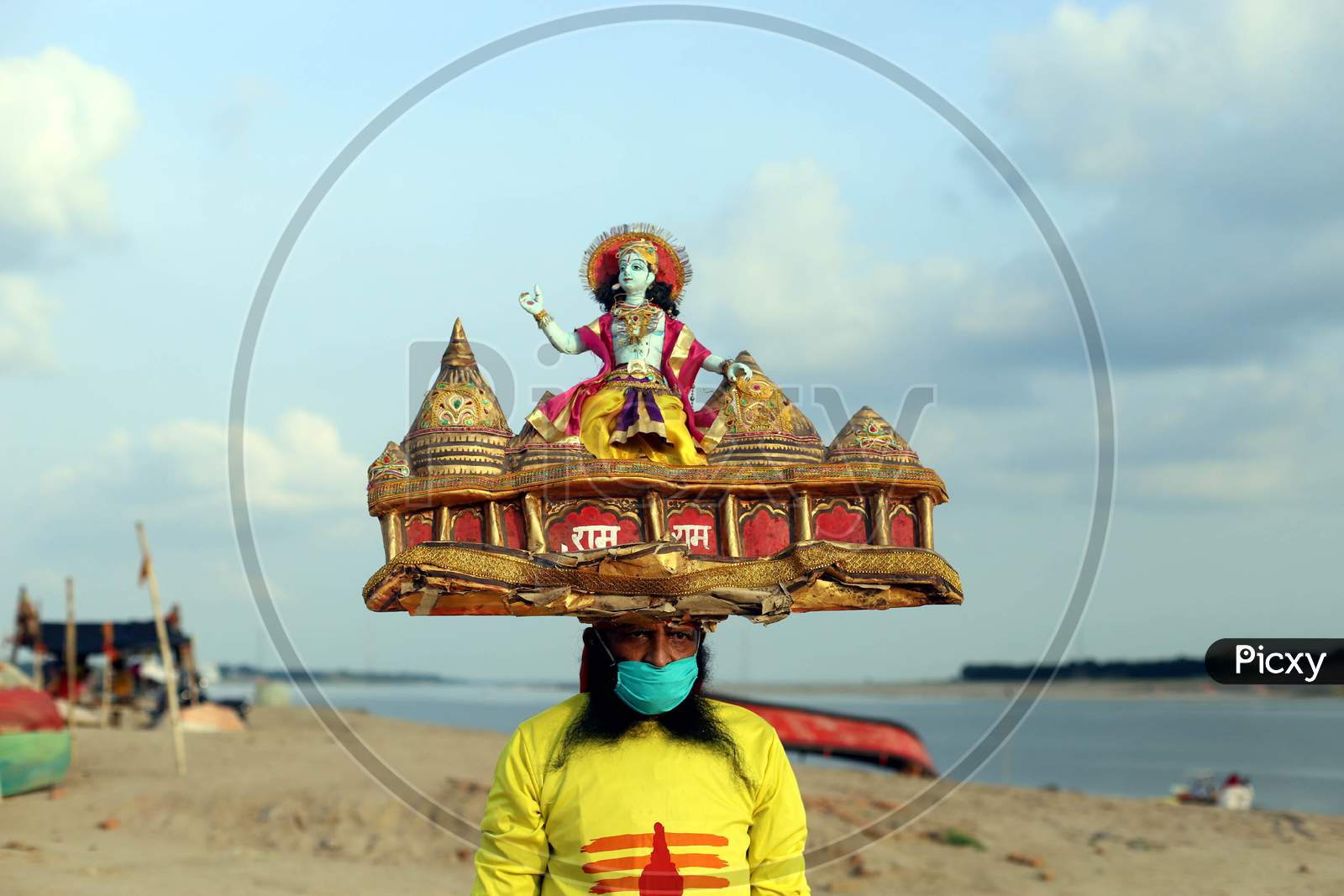 A man holds sculpture of Ram Temple on his head, ahead of the foundation ceremony of Ram temple in Ayodhya, on the banks of River Ganga at Sangam, in Prayagraj, August 4, 2020.