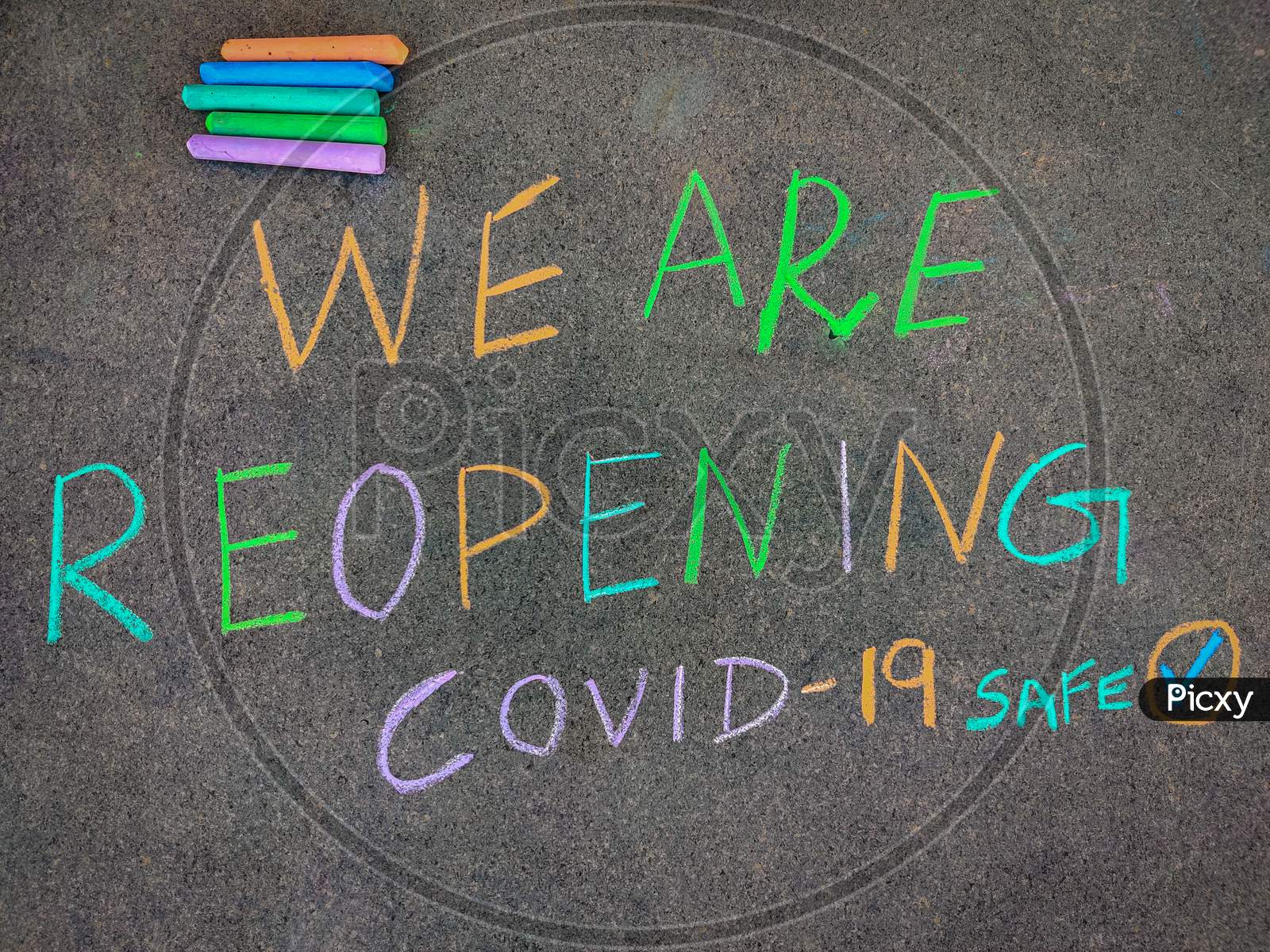 The Inscription Text On The Grey Board "We Are Reopening". Using Color Chalk Pieces.