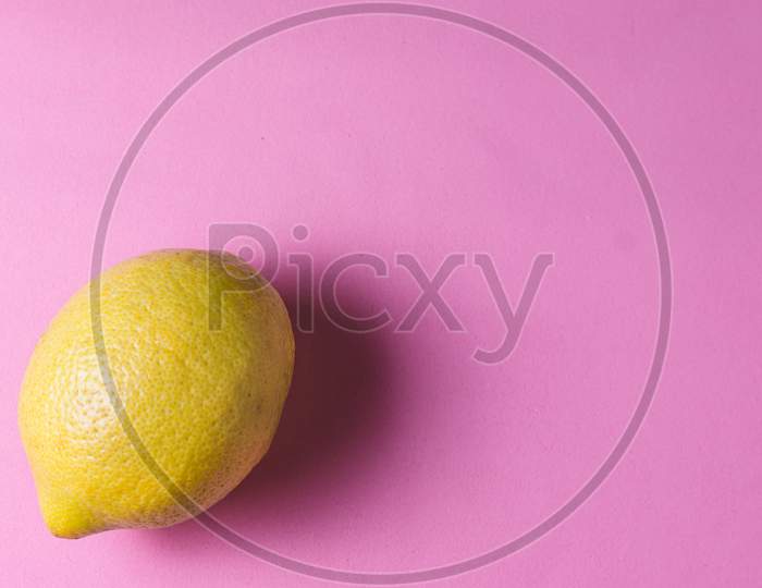 A yellow lemon on a rose background