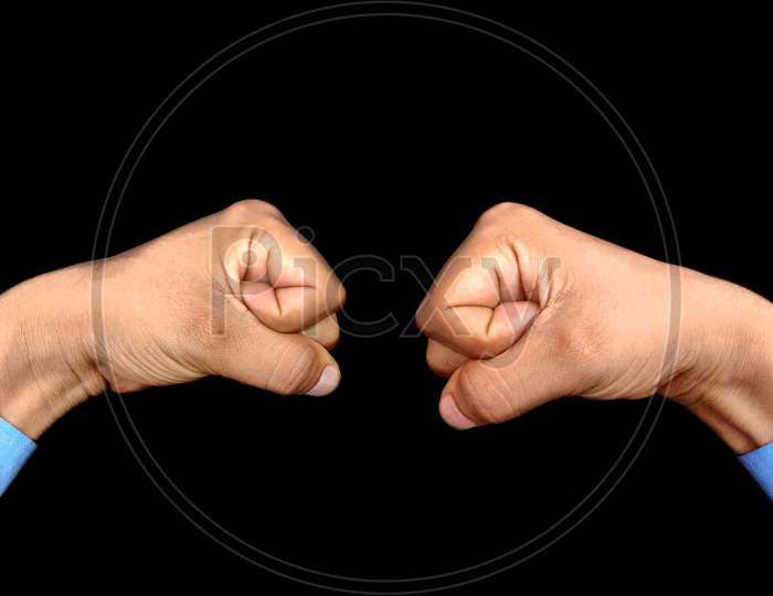 Hand fist opposite of another male hand fist wearing blue shirt, corporate opposition Concept, black background
