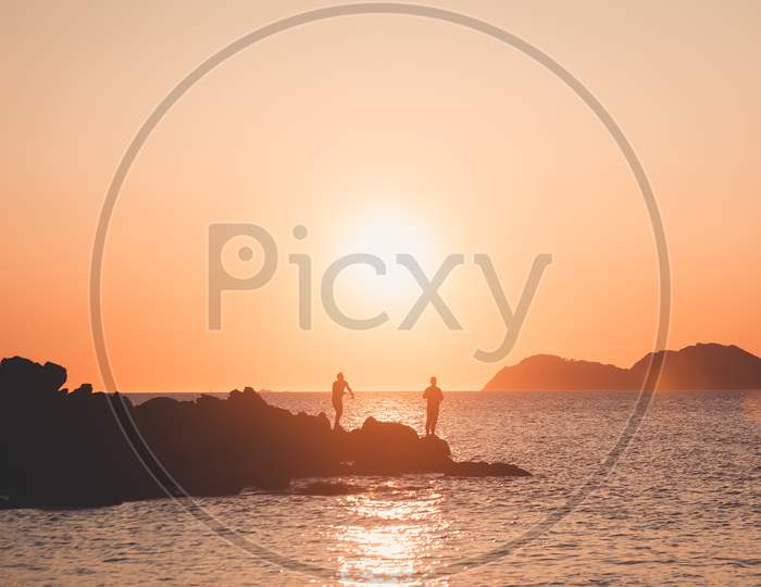 Two Fishermen Silhouette During A Sunset