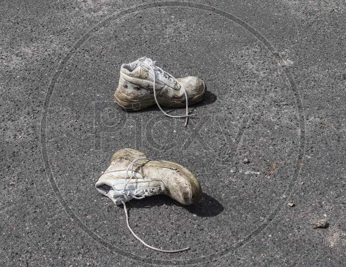 Concept Of Old Shoes Left On An Ashpalt Road With Copy Space For Text.