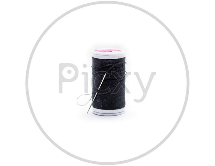 A Needle And Black Thread For Sewing Against White Background