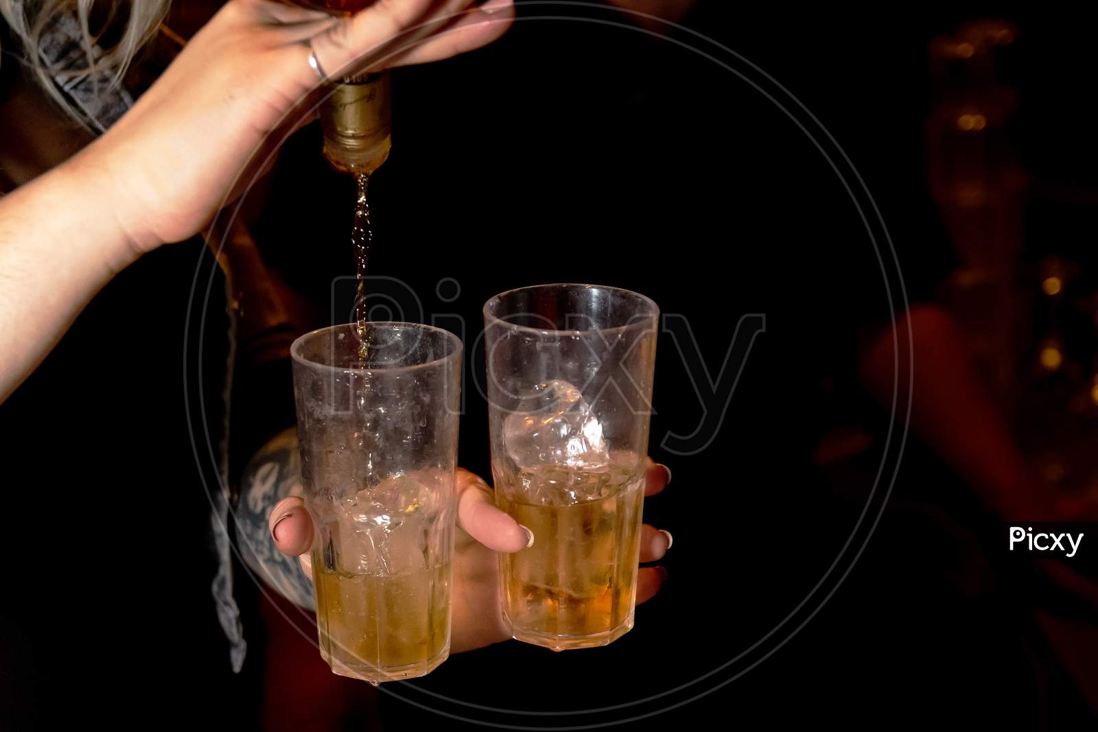 Woman Serving Drink In Two Glasses