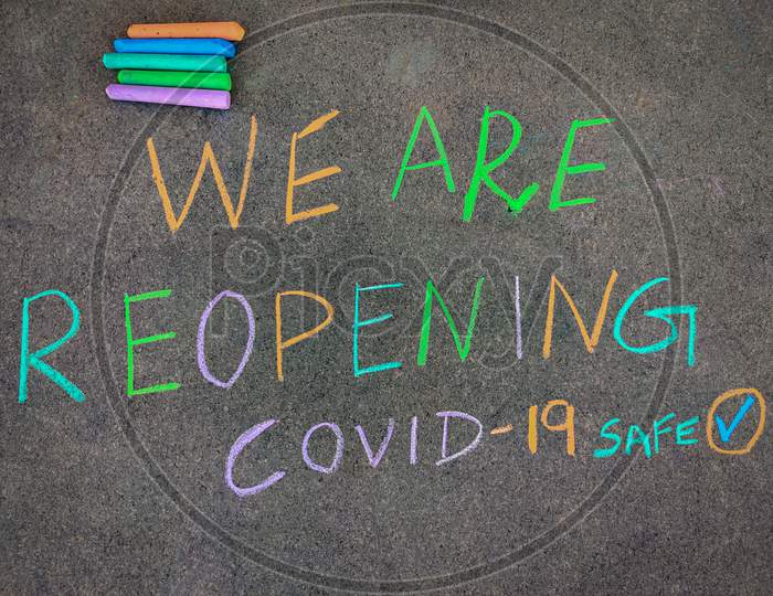 The Inscription Text On The Grey Board "We Are Reopening". Using Color Chalk Pieces.
