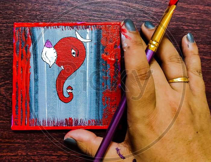 An artist's hand with a Lord Ganesha.