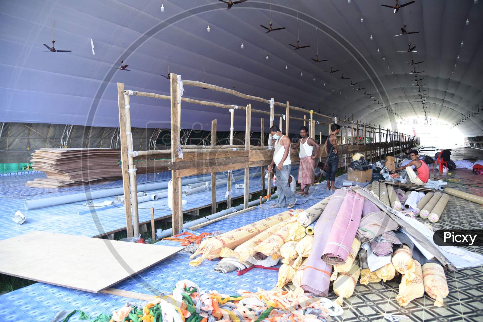 Workers carry materials for the construction of a COVID care centre for the treatment of COVID-19 infected patients, at Nehru Stadium in Guwahati on August 3, 2020.