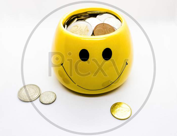 Close Up Saving Money As Coins In A Smiley Little Cup Against White Background