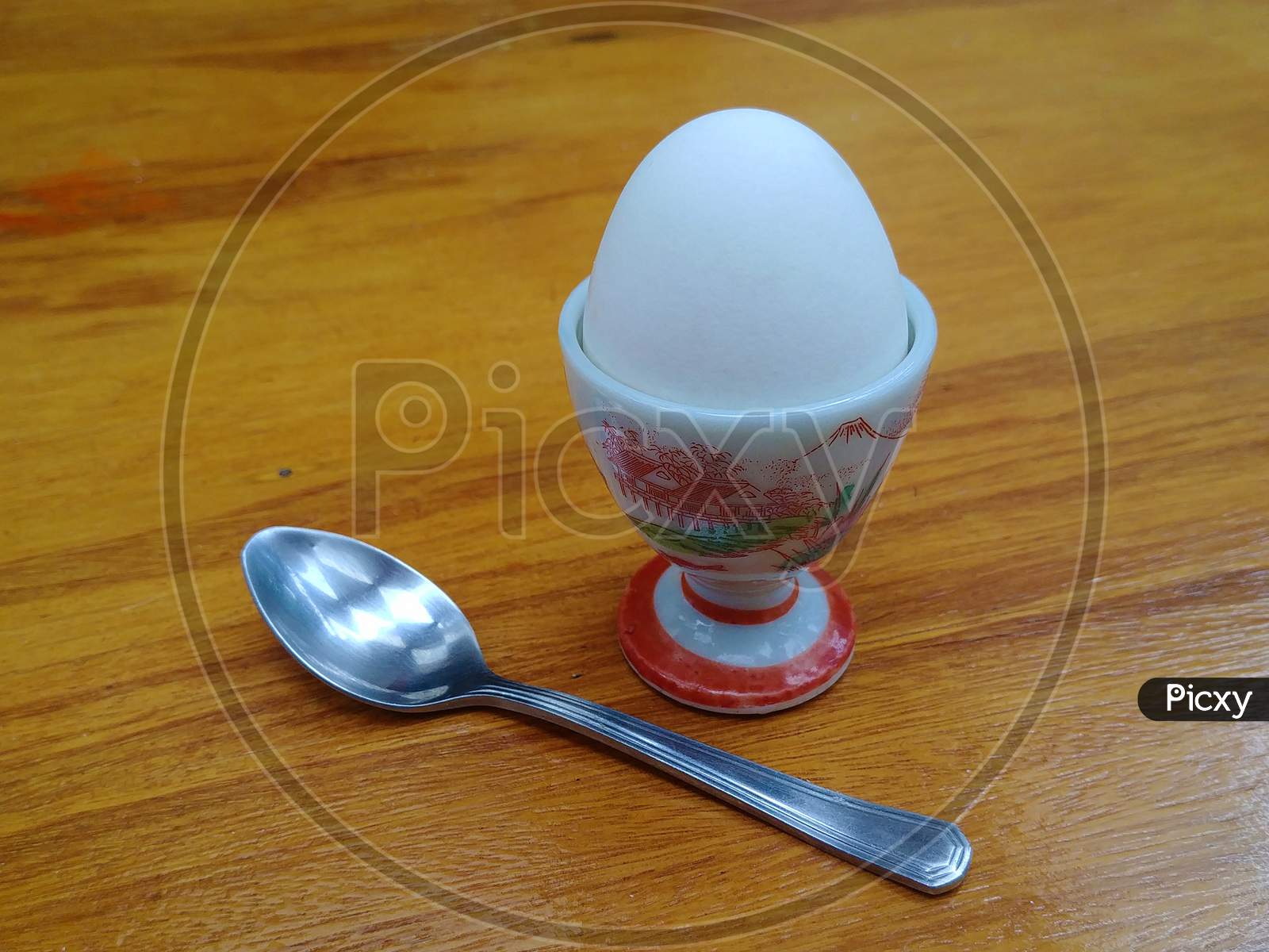 Delicate boiled egg holder with a spoon on the wooden table.