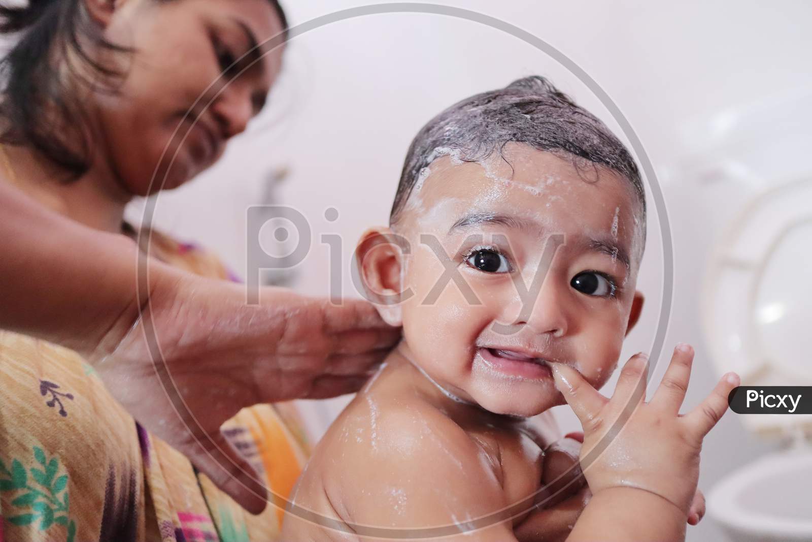 Indian Baby Enjoying Bubble Bath With Foam While Mother Rubs Soap On His Back
