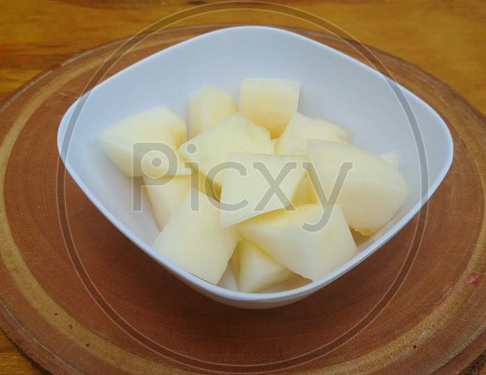 White melon cut into slices in a square bowl on a wooden base