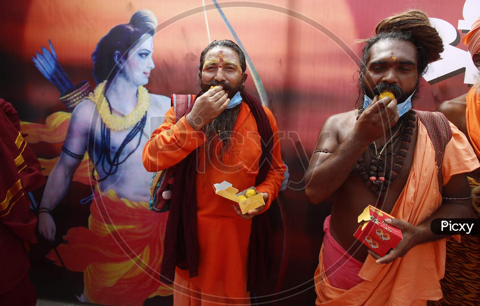 Holy men eat sweets at BJP local office during celebrations of the stone laying ceremony of the Ram Temple by Prime Minister Narendra Modi in Ayodhya, in Chandigarh August 5, 2020