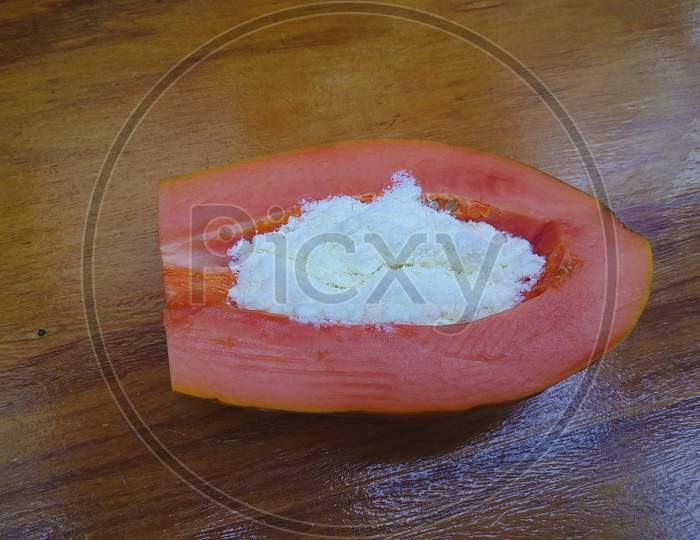 Brazilian papaya with powdered milk on the wooden table