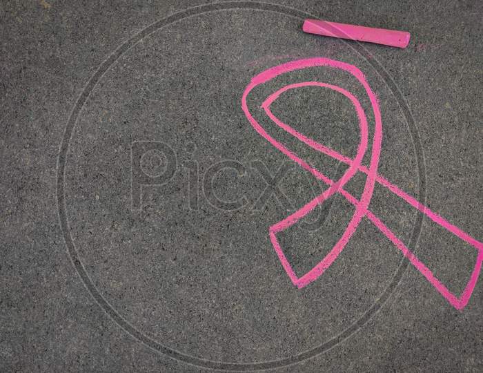 Breast Cancer Awareness Ribbon Hand Drawn Using Pink Color Chalk On Grey Background.