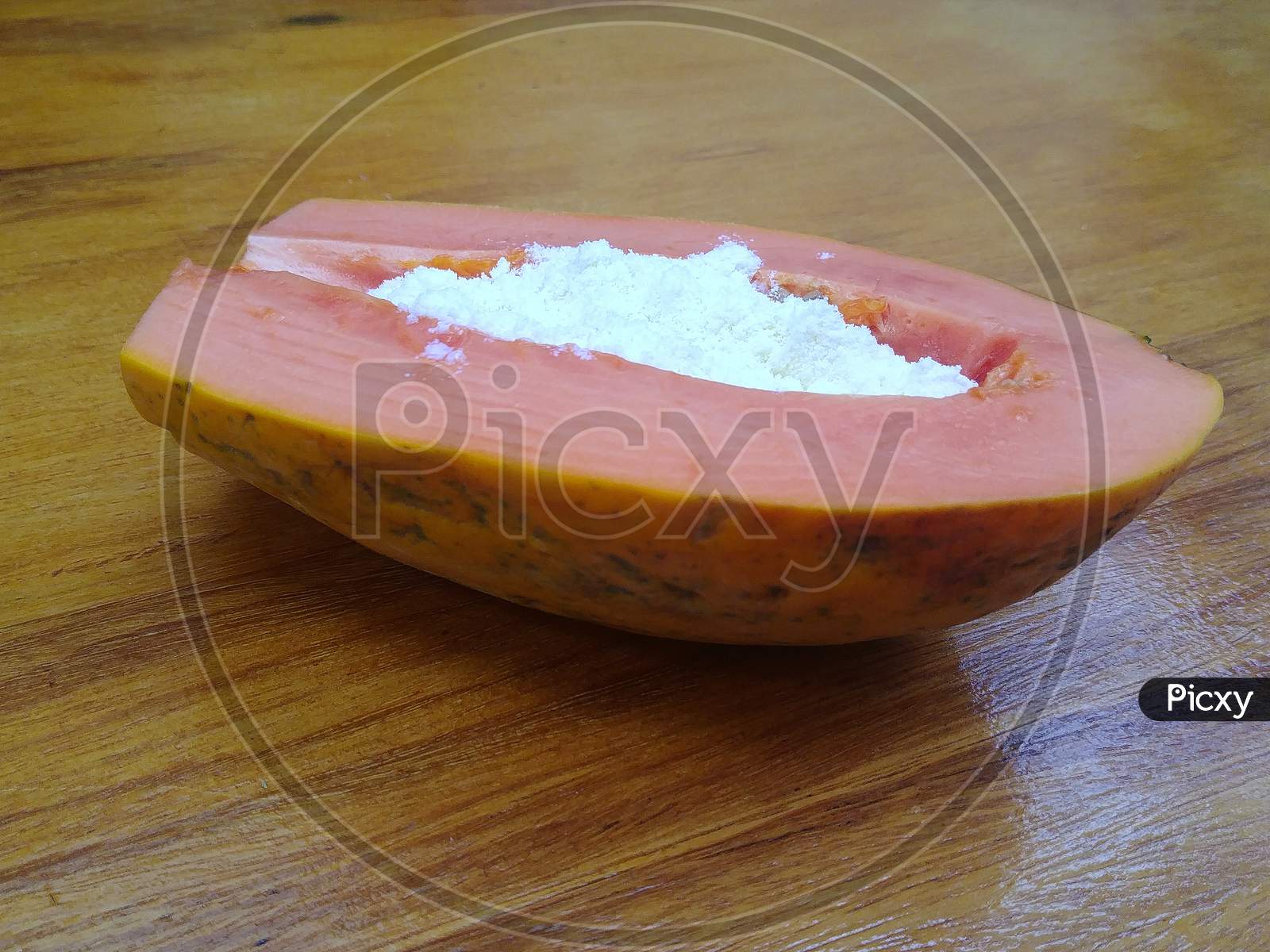 Delicious Brazilian papaya covered with powdered milk on a wooden table