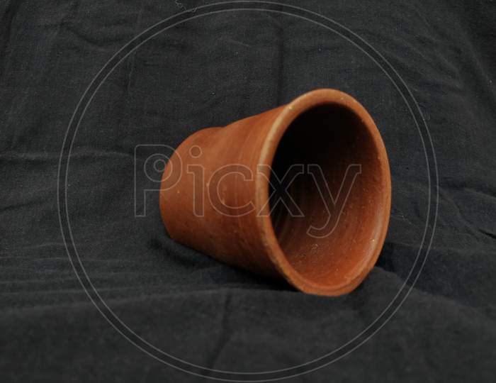 Empty Handmade Sand or Clay Red Glass isolated on Black Background