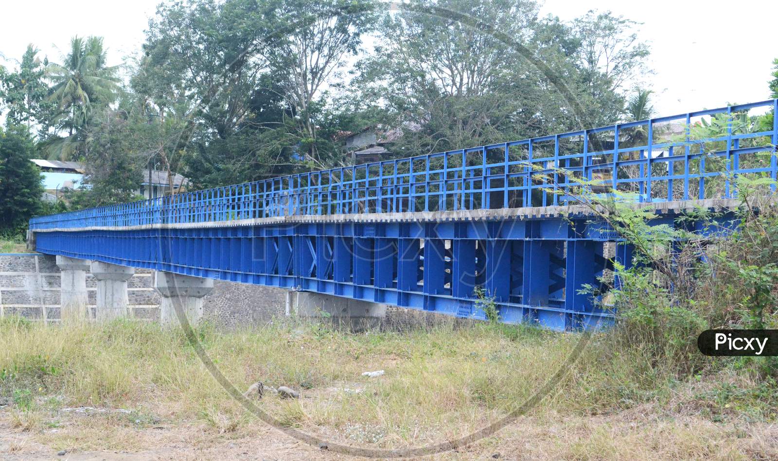 Long Iron Bridge Building In Blue Paint Connecting The Two Regions