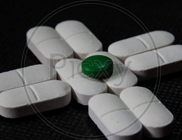 Tablets Or Pills Are Kept As Plus Sign On Desk With Black Back Ground.
