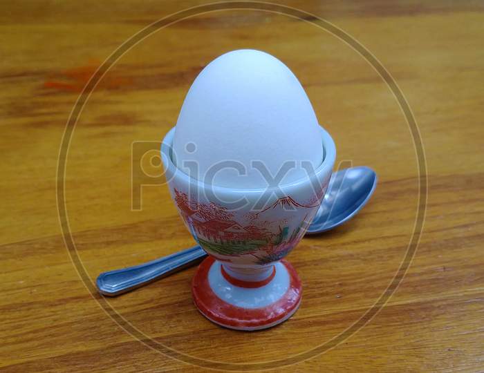 Delicate boiled egg holder with a spoon on the wooden table.