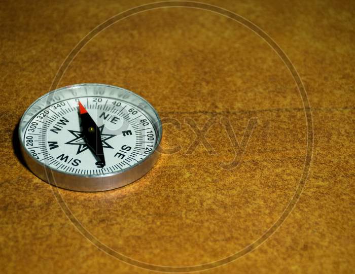 A Compass Pointing North On A Brown Textured Background With Empty Space