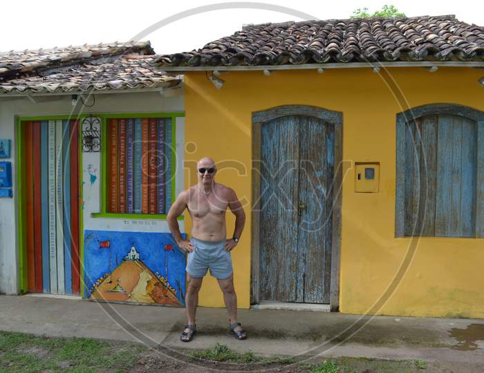 Mature and muscular man wearing sunglasses in front houses in Trancoso