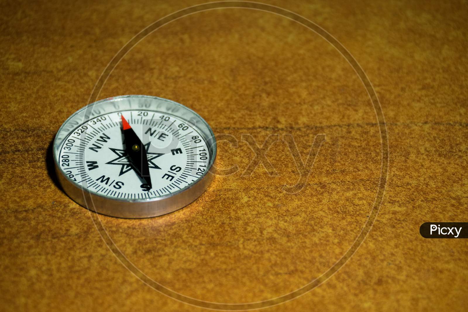 A Compass Pointing North On A Brown Textured Background With Empty Space